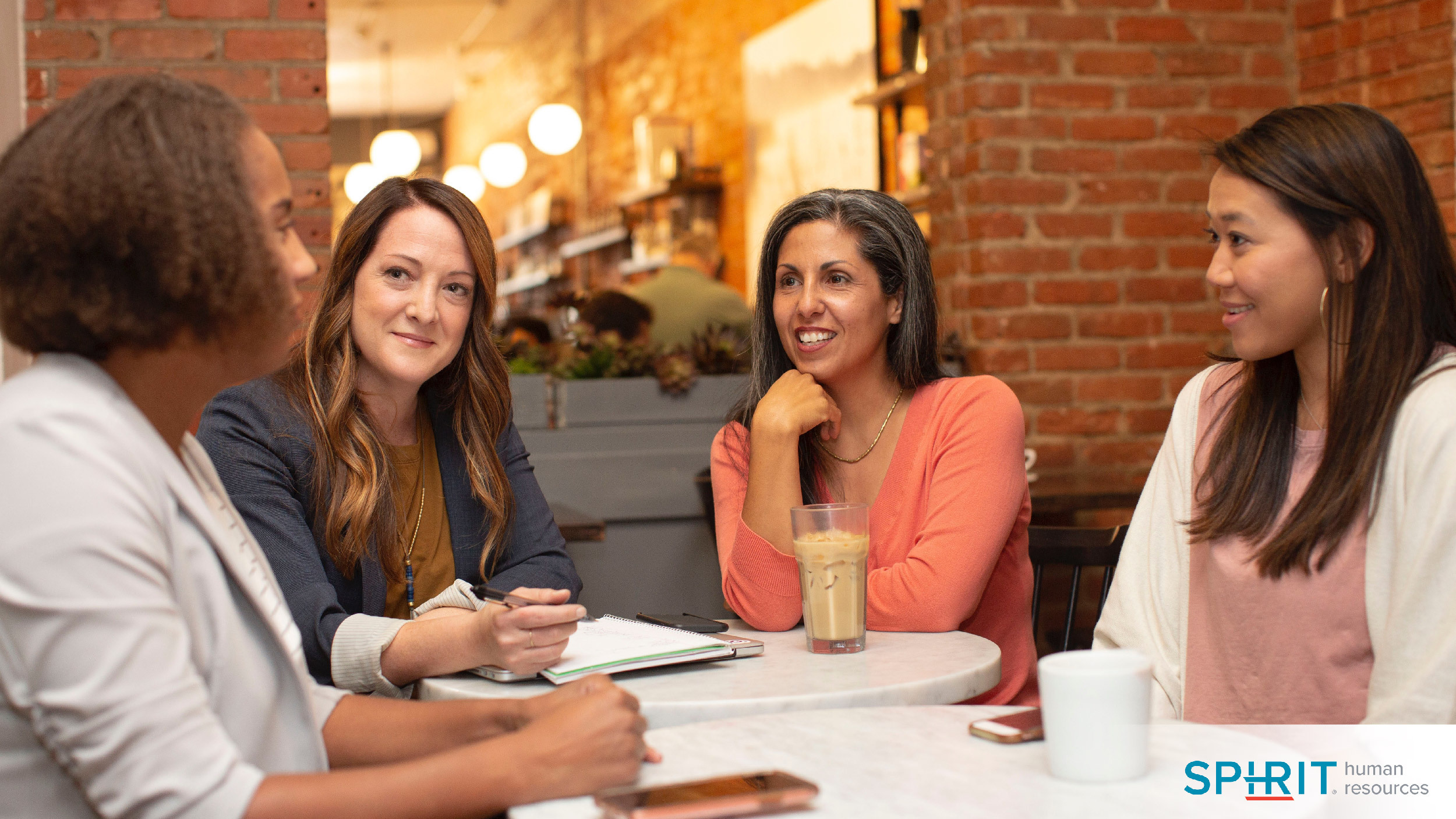 four women sitting around a table talking